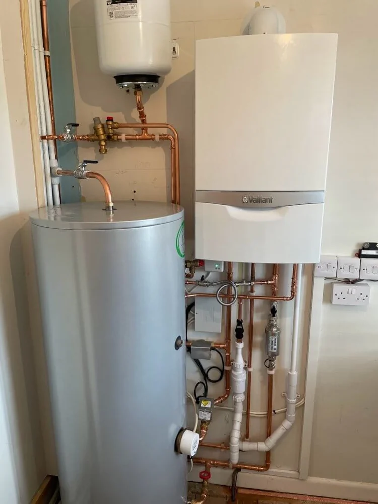 Wall-mounted Vaillant boiler beside a hot-water cylinder, expansion vessel and copper pipework.
